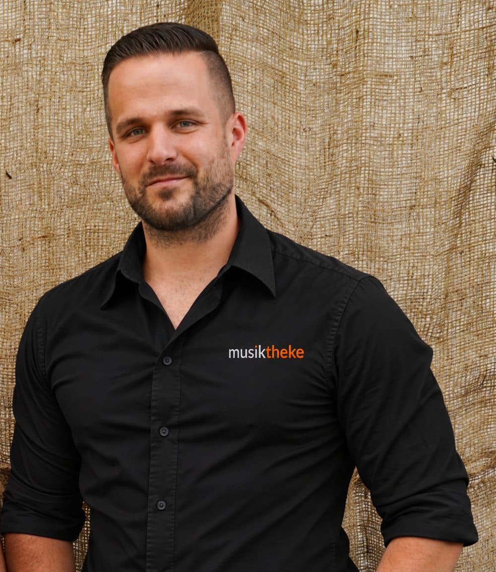 Felix Kremer von der Musiktheke im schwarzen Hemd mit Musiktheke-Logo